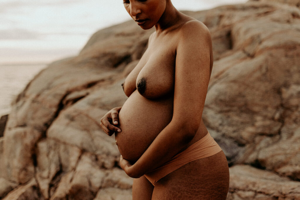 en gravid mamma under sin gravidfotografering håller om sin mage iklädd underkläder