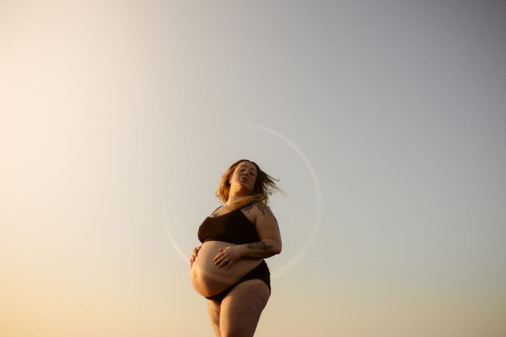 en gravid kvinna slänger med håret bakåt iklädd underkläder