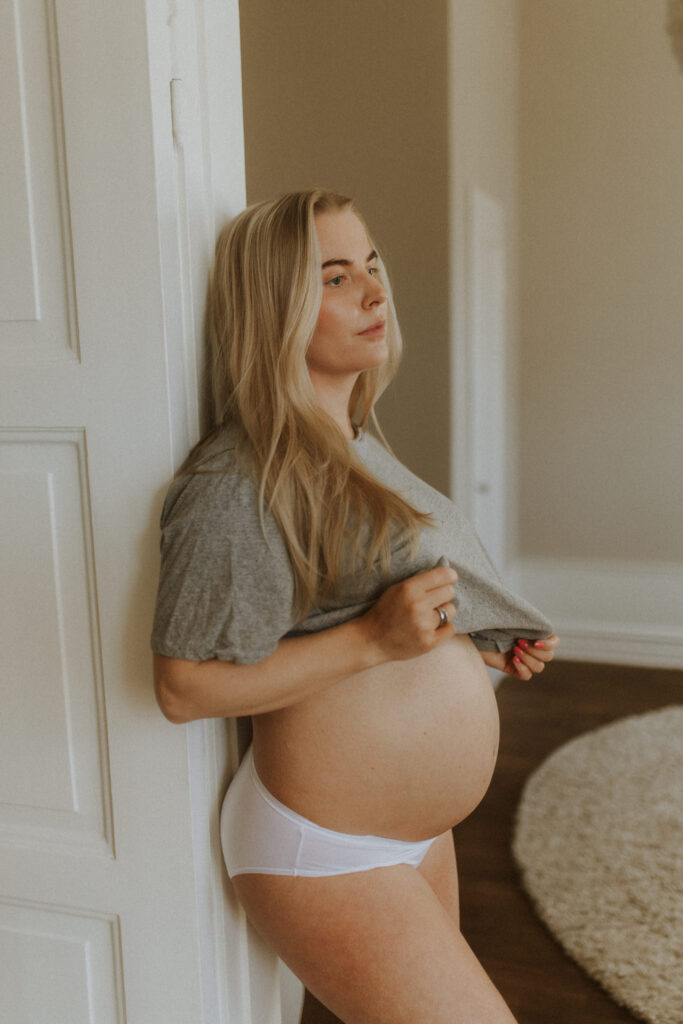 karoline pettersson gravid lutar sig mot en dörrkarm under sin gravidfotografering