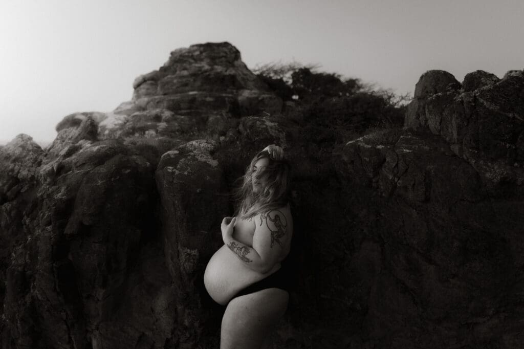 gravidfotografering på vintern i Göteborg, gravid kvinna på klipporna vid havet i svartvitt