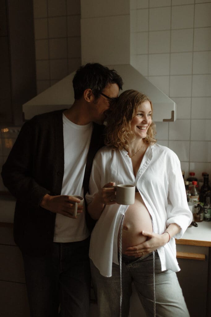gravid kvinna och hennes man i köket hemma en mörk decemberdag, gravidfotografering i Göteborg