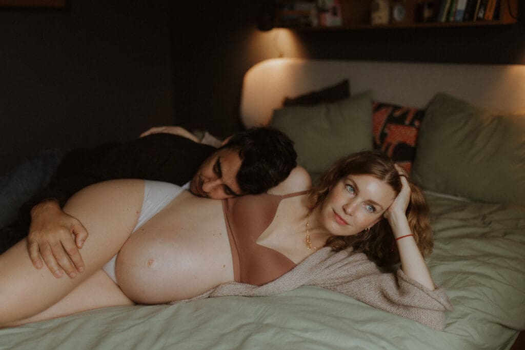 gravid mamma och hennes man vilar tillsammans i sängen hemma, gravidbilder på vintern