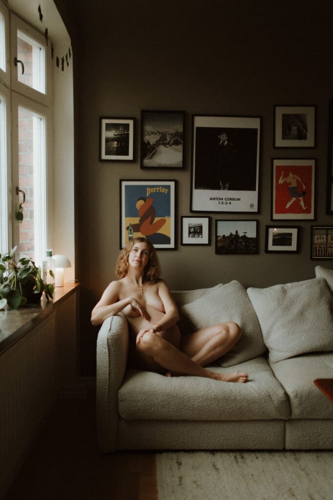 gravid kvinna i en soffa med mjukt vinterljus från fönstret
