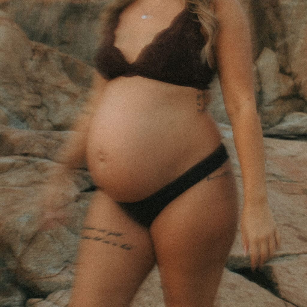 gravid kvinna i bruna spetsunderkläder vid klipporna på västkusten