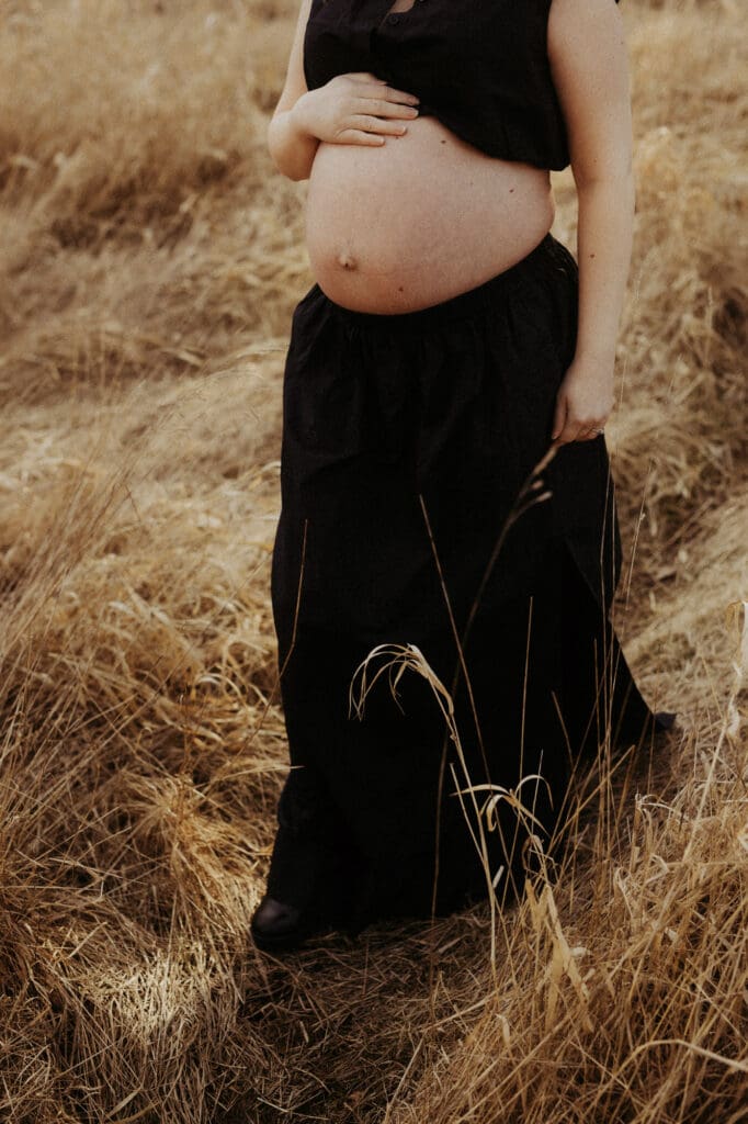 gravid mage och lång svart kjol på ett fält under vintern